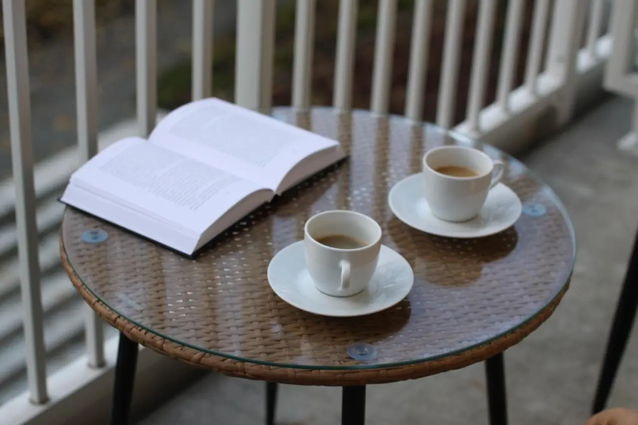Two cups of coffee and an open book on the balcony table