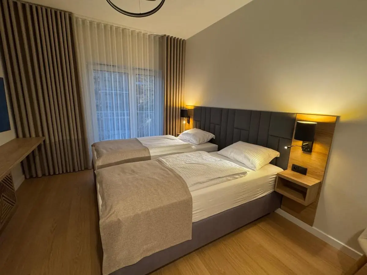 The bed made up with a beige throw, reading lamps on both sides